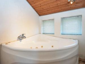 a white tub in a bathroom with two windows at 8 person holiday home in Juelsminde in Sønderby