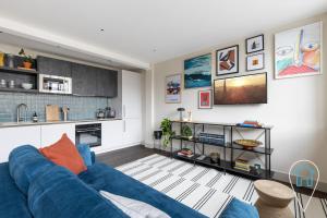 uma sala de estar com um sofá azul e uma cozinha em Modern 1BR home in Islington! em Londres