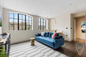 uma sala de estar com um sofá azul e janelas em Modern 1BR home in Islington! em Londres