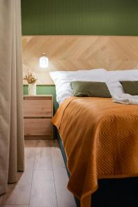 1 cama con manta naranja y mesita de noche en Greenside SunPark Apartament en Przemyśl