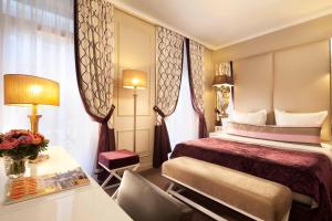 パリにあるオテル ガリレオ シャンゼリゼのベッドとテーブルが備わるホテルルームです。