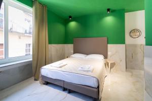 ein Schlafzimmer mit einem Bett mit einer grünen Wand in der Unterkunft P.C. Boutique H. Vesuvius, Napoli Centro, by ClaPa Group in Neapel