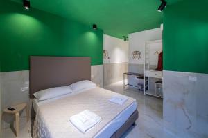ein Schlafzimmer mit einer grünen Wand und einem Bett in der Unterkunft P.C. Boutique H. Vesuvius, Napoli Centro, by ClaPa Group in Neapel