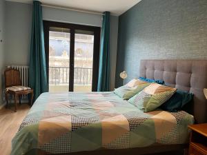 een slaapkamer met een bed en een groot raam bij Appartement d’artiste lumineux central 76m2 in Perpignan