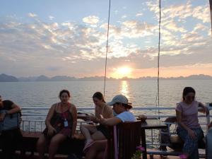 un gruppo di persone seduti intorno a un tavolo su una barca di Tom's Family Hotel a Ha Long