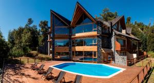 una casa con piscina frente a ella en Hosteria La Camila en Villa La Angostura
