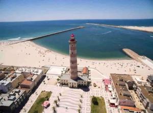 a lighthouse on the beach next to a beach at Corrente do Oudinot perto da praia in Gafanha da Nazaré +8 photos