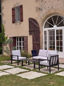 two benches and a table in front of a building at Le Logis du Pradet in Moncrabeau