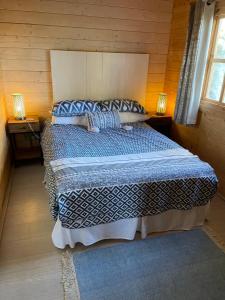 een slaapkamer met een bed met een blauw dekbed en 2 lampen bij O Dan Y Coed Swedish Log Cabin with New 2024 Wood Fired Hot Tub in Chwilog