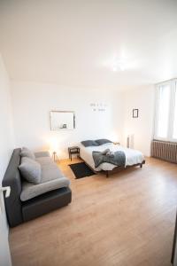 Habitación blanca con cama y sofá en Aux portes de Lyon Tout confort emplacement idéale Netflix, en Givors