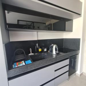 a kitchen counter with a sink and a microwave at Lindo Flat no Jardim Oceania - Get One in João Pessoa
