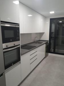 una cocina con armarios blancos y electrodomésticos negros en Modern & sunny apartment near Valencia, en Paiporta