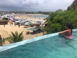 a woman sitting in a swimming pool next to a beach at Muyuyo Lodge in Ayangue