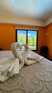 two towel swans making a heart on a bed at Cabañas Del Sol in Valle Grande