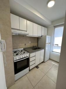 a kitchen with white cabinets and a stove and refrigerator at NGL - Departamento temporal con cochera in Santa Fe