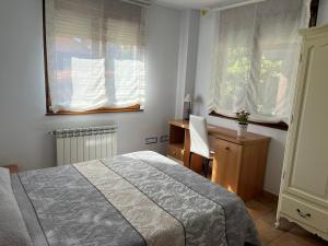 een slaapkamer met een bed, een bureau en 2 ramen bij Apartamentos casa luis in Suances