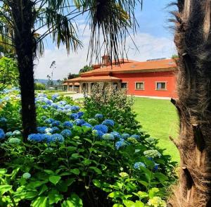 a garden with blue flowers in front of a building at Villam Natura & Spa in Vila Nova de Famalicão