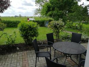 a patio with a table and chairs and a field at Kleine Scholle in Neuharlingersiel