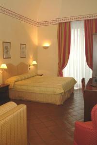 カターニアにあるホテル ラ ヴィレのベッド2台とソファが備わるホテルルームです。