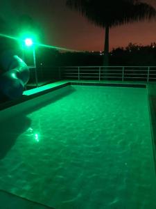 una persona sosteniendo una luz en una piscina por la noche en Chácara em Mairinque - Porta do Sol com seg 24 hs en Mairinque