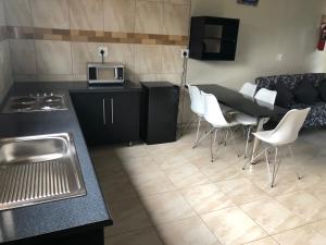 a kitchen with a table and white chairs in a room at Dam Vista Retreat in Giyani