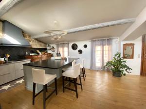 a kitchen with a black table and white chairs at Au rep&egrave;re d'Argante in P&eacute;zenas