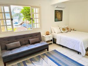 um quarto com um sofá, uma cama e uma janela em Casa Amarela em Angra dos Reis