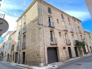 un grand bâtiment en briques avec un garage dans une rue dans l'établissement Au repère d'Argante, à Pézenas