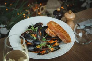 a plate of mussels and bread on a table with wine glasses at Wellton Riga Hotel & SPA in Riga