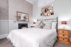 a bedroom with a white bed and a fireplace at Bramblewick in Whitby