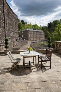une table et deux chaises assises sur une terrasse dans l'établissement New Lanark Self Catering Waterhouses, à Lanark
