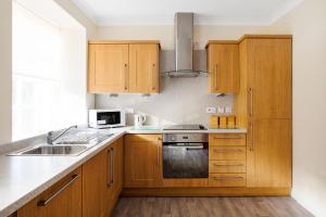 uma cozinha com armários de madeira e um lavatório em New Lanark Self Catering Waterhouses em Lanark