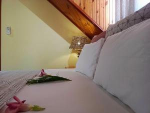 un letto con cuscini bianchi e un fiore rosa di Badamier Self-Catering a La Digue