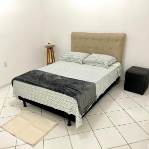 a bed in a room with a white tiled floor at Apartamento aconchegante próx ao Centro - 1 quarto in Vitória da Conquista