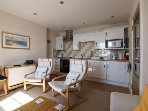 a kitchen with white cabinets and white chairs at Quayside Cottage in North Berwick