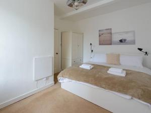a white bedroom with a large bed with two towels on it at Pebbles Apartment in North Berwick