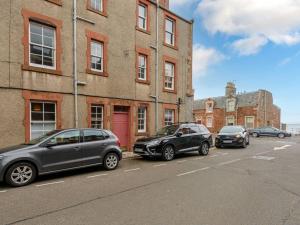 three cars parked in a parking lot in front of a building at Pebbles Apartment in North Berwick