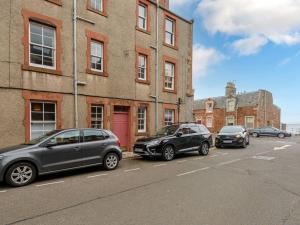 drei Autos auf einem Parkplatz vor einem Gebäude geparkt in der Unterkunft Pebbles Apartment in North Berwick