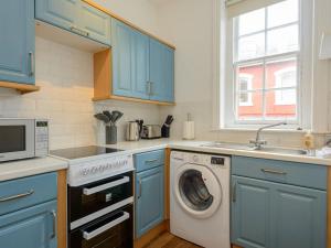 une cuisine avec des armoires bleues et un lave-linge dans l'établissement Pebbles Apartment, à North Berwick
