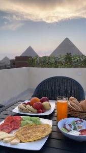 einem Tisch mit zwei Teller Essen und einem Glas Orangensaft in der Unterkunft Hur Pyramids Inn in Kairo