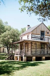 una antigua cabaña de madera con porche y terraza en Contigo Ranch Fredericksburg en Fredericksburg