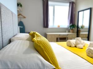 uma cama com lençóis e almofadas amarelos e brancos em Sea View Family Stay by Beach Gym & Parking em Bournemouth