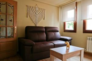 a living room with a leather couch and a table at Urbión Etxea in Viana