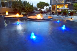 een zwembad met drie vuurkorven met blauwe verlichting bij Ejecutivo Express Guadalajara Providencia - Av México in Guadalajara