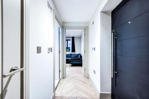 a hallway with a black door and a living room at Lovely 1-bed flat with a balcony & garden access in London