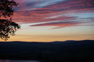 una puesta de sol sobre las montañas con un árbol en Silver Well Cottage, en Ilkley