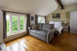 a bedroom with a couch and a bed and windows at Silver Well Cottage in Ilkley