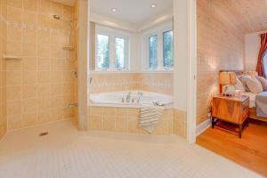 a bathroom with a bath tub and a bed at Waterfront Muskoka Cottage with Hot Tub & Game Room in Bracebridge