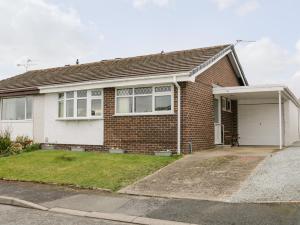 a red brick house with a white garage at 17 Ffordd Gwenllian in Llanfairpwllgwyngyll