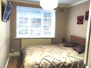 a bed in a bedroom with a large window at 2 Bed Flat Near Station with Parking&Comgarden in Sutton